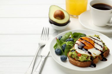 Avokado tostlu sağlıklı kahvaltı beyaz ahşap masada servis edilir, yakın plan. Metin için boşluk