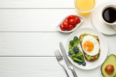 Beyaz ahşap masada servis edilen avokado tostlu sağlıklı bir kahvaltı. Metin için boşluk