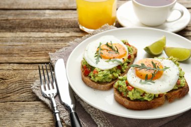 Avokado tostlu sağlıklı kahvaltı ahşap masada servis edilir, yakın plan. Metin için boşluk