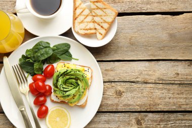 Tahta masada servis edilen avokado tostlu lezzetli bir kahvaltı. Metin için boşluk