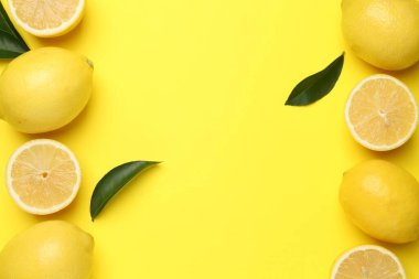 Sarı arka planda olgun limon ve yaprakların çerçevesi düz. Metin için boşluk