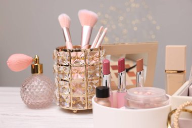 Makyaj ürünleri açık ahşap masa üzerinde gri arka planda, yakın plan. Bokeh etkisi