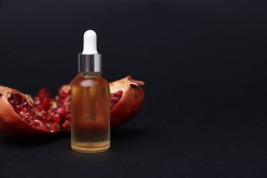 Bir şişe esaslı yağ ve nar, koyu arka planda, yakın plan. Metin için boşluk