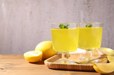 Tatlı kaselerinde lezzetli sarı jöle, nane ve ahşap masada taze limon, yakın plan. Metin için boşluk
