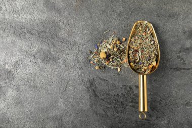 Kurumuş yeşil çay yaprakları ve gri masadaki metal spatula, üst manzara. Metin için boşluk