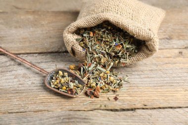 Çuvalda kurutulmuş bitki çayı ve ahşap masada metal spatula, yakın plan.