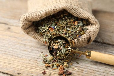 Çuvalda kurutulmuş bitki çayı ve tahta masada kaşık, yakın plan.