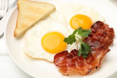 Beyaz ahşap masada servis edilen yağda yumurta ve pastırmalı nefis bir kahvaltı.