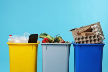 Çöpler açık mavi arka planda çöp kutularında, yakın plan. Atık sıralama