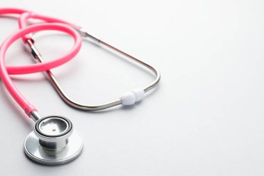 Açık gri arka planda pembe steteskop, yakın plan. Metin için boşluk