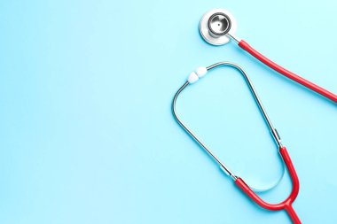 Açık mavi arka planda kırmızı steteskop, üst manzara. Metin için boşluk