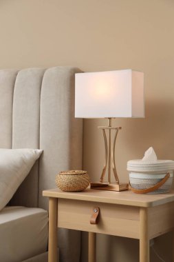 Şık lamba, hasır kutu ve sepet evdeki komodinin yanında.