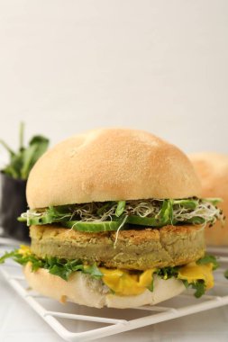 Vejetaryen köfteli lezzetli hamburger ve sebzeler beyaz fayanslı masada servis edilir, yakın plan.