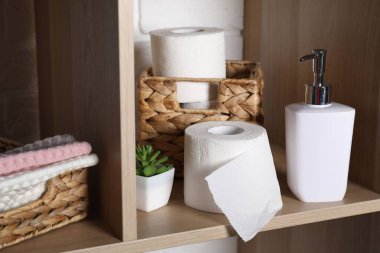 Tuvalet kağıdı ruloları, sabun, havlu ve tuvalet odasındaki ahşap rafta saksı, yakın plan.