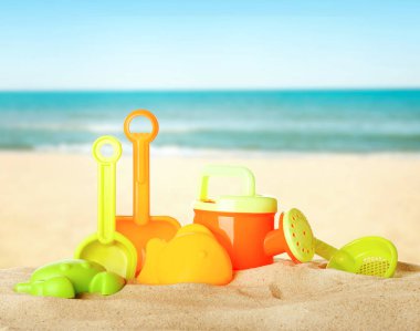 Deniz kenarındaki kumda parlak plastik plaj oyuncakları. Yaz zamanı.