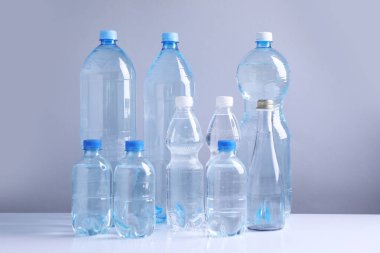 Beyaz masada gri arka planda farklı boyutlarda su şişeleri