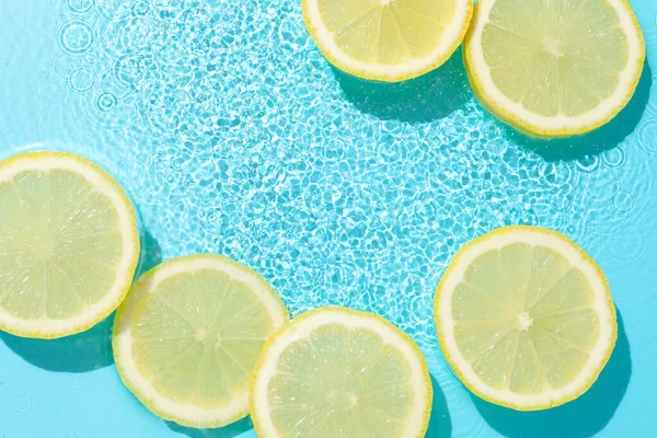 Açık mavi arka planda limon dilimleri, düz. Metin için boşluk