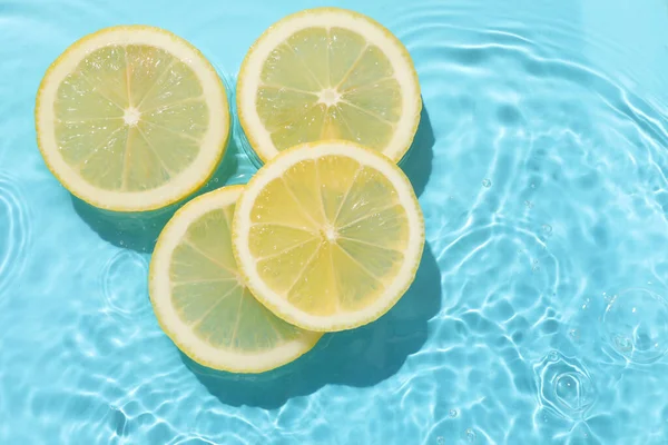 Açık mavi arka planda limon dilimleri, düz. Metin için boşluk