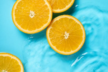 Açık mavi zemin üzerinde portakal dilimleri, düz uzanmış.