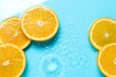 Açık mavi zemin üzerinde portakal dilimleri, düz uzanmış.