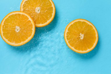 Açık mavi zemin üzerinde portakal dilimleri, düz uzanmış.