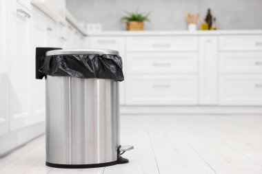 Mutfakta yerde plastik torba olan metal çöp kutusu, metin için yer