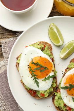 Tahta masada servis edilen avokado tostlu sağlıklı bir kahvaltı.