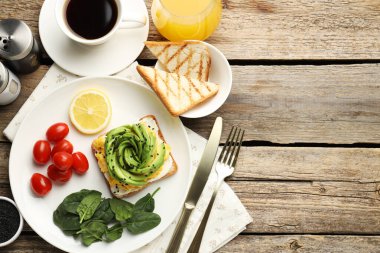 Tahta masada servis edilen avokado tostlu lezzetli bir kahvaltı. Metin için boşluk