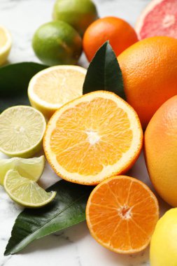 Beyaz mermer masada farklı olgun narenciye meyveleri, yakın plan.