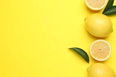 Olgun limon ve yapraklar sarı arka planda, düz yerde. Metin için boşluk