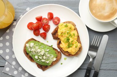 Gri ahşap masada servis edilen lezzetli avokado tostlu sağlıklı bir kahvaltı.