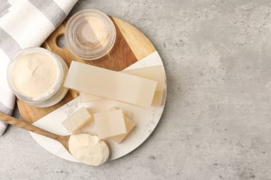 Jelatin tozu, jöle parçaları ve gri desenli masa üzerinde bir bardak su, üst manzara. Metin için boşluk