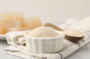 Kasede jelatin tozu, gri masada kaşık ve jöle küpleri, yakın plan.