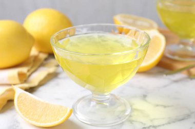 Tatlı kasesinde leziz sarı jöle ve beyaz mermer masada taze limonlar, yakın plan.