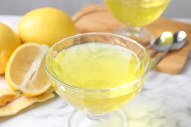 Tatlı kasesinde leziz sarı jöle ve beyaz mermer masada taze limonlar, yakın plan.