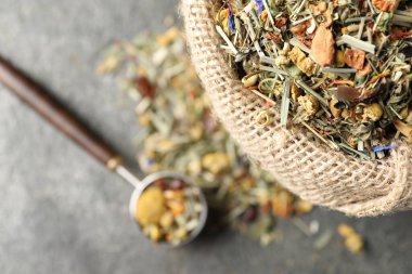 Torbada kurutulmuş bitki çayı ve gri masada ölçü kaşığı.