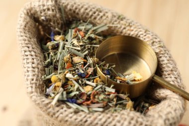 Torbada kurutulmuş bitki çayı ve masada ölçü kaşığı, yakın plan.