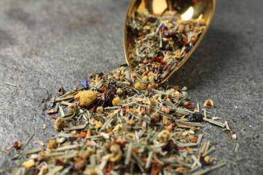 Gri masada kurumuş yeşil çay yaprakları ve metal spatula, yakın plan.