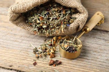 Çuvalda kurutulmuş bitki çayı ve tahta masada kaşık, yakın plan.