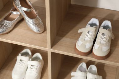 Raf ünitesinde farklı stil çocuk ayakkabıları var. Kapalı, yakın çekim.