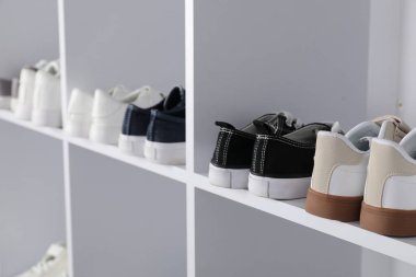 Raf ünitesinde farklı stil çocuk ayakkabıları var. Kapalı, yakın çekim.