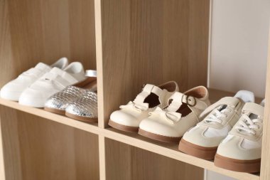 Raf ünitesinde farklı stil çocuk ayakkabıları var. Kapalı, yakın çekim.