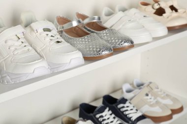 Raf ünitesinde farklı stil çocuk ayakkabıları var. Kapalı, yakın çekim.