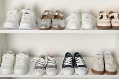 Raf ünitesinde farklı stil çocuk ayakkabıları var. Kapalı, yakın çekim.