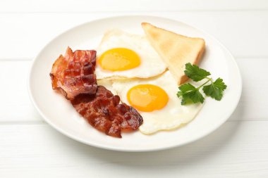 Beyaz ahşap masada servis edilen yağda yumurta ve pastırmalı nefis bir kahvaltı.