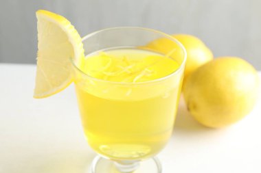 Tatlı kasesinde leziz sarı jöle ve beyaz masada limonlar, yakın plan.