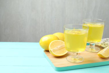 Tatlı kaselerinde leziz sarı jöle ve açık mavi ahşap masada limonlar, yakın plan. Metin için boşluk