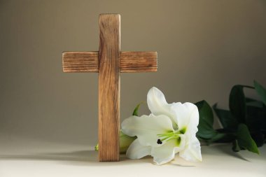 Paskalya. Ahşap haç ve bej arka planda güzel zambak çiçekleri, yakın plan.