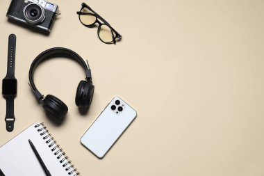 Kulaklıklar, klasik kamera, akıllı saat, akıllı telefon, bej arka planda gözlük ve kırtasiye malzemesi, düz yatak. Metin için boşluk