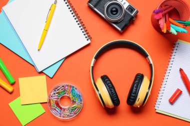Kulaklıklar, klasik kamera ve turuncu arka planda kırtasiye malzemesi, düz konum